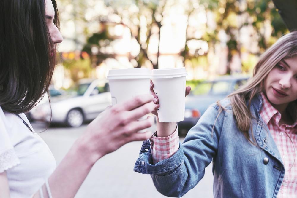 Two women pictured holding paper cups