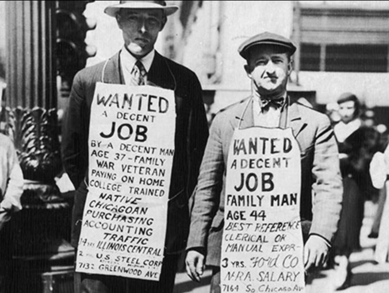 Two men walk around NYC during the Great Depression with apron signs that read “Wanted A Decent Job”