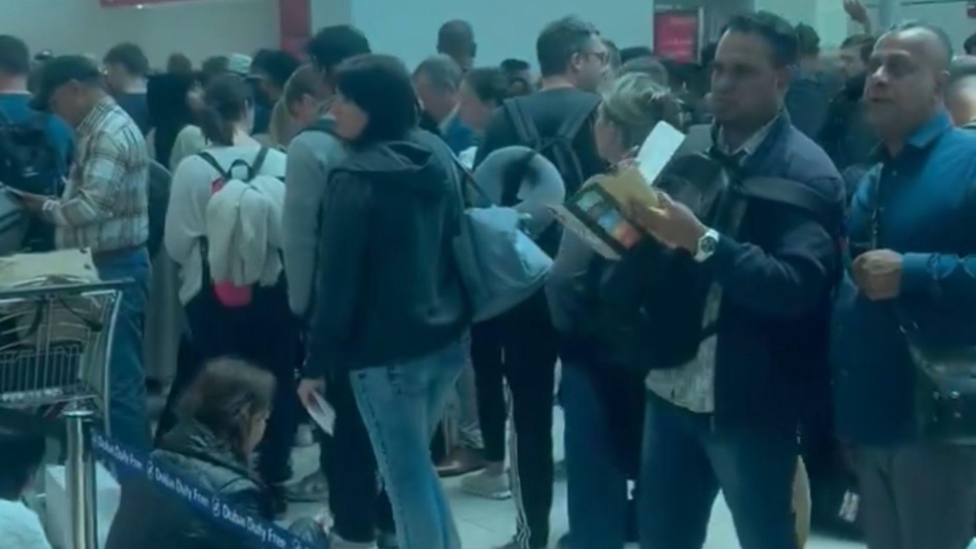 Passengers in Dubai airport are stranded due to the flooding. A crowd of people is cramped together. Some are standing, and others are sitting on the floor.