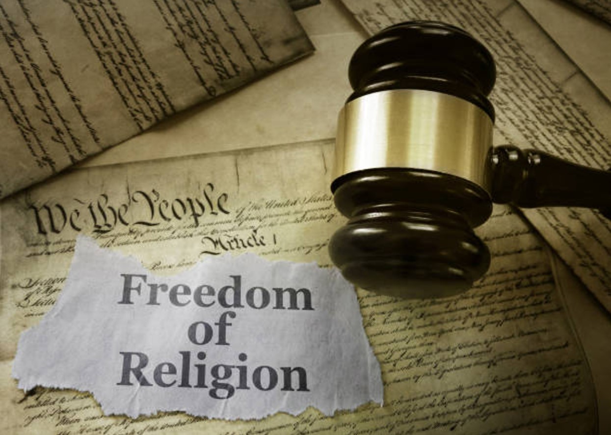 Photograph of the US Constitution with a small piece of paper that reads “Freedom of Religion” and a judge’s gavel