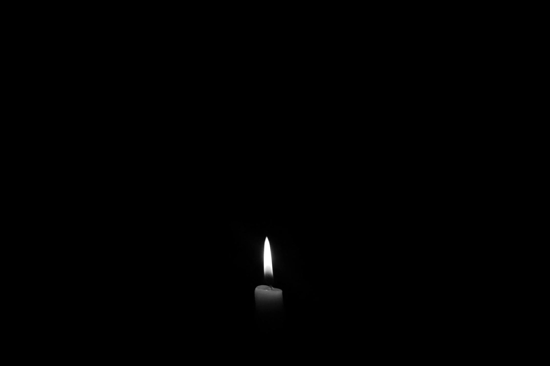 A black and white image of a candle in a dark space