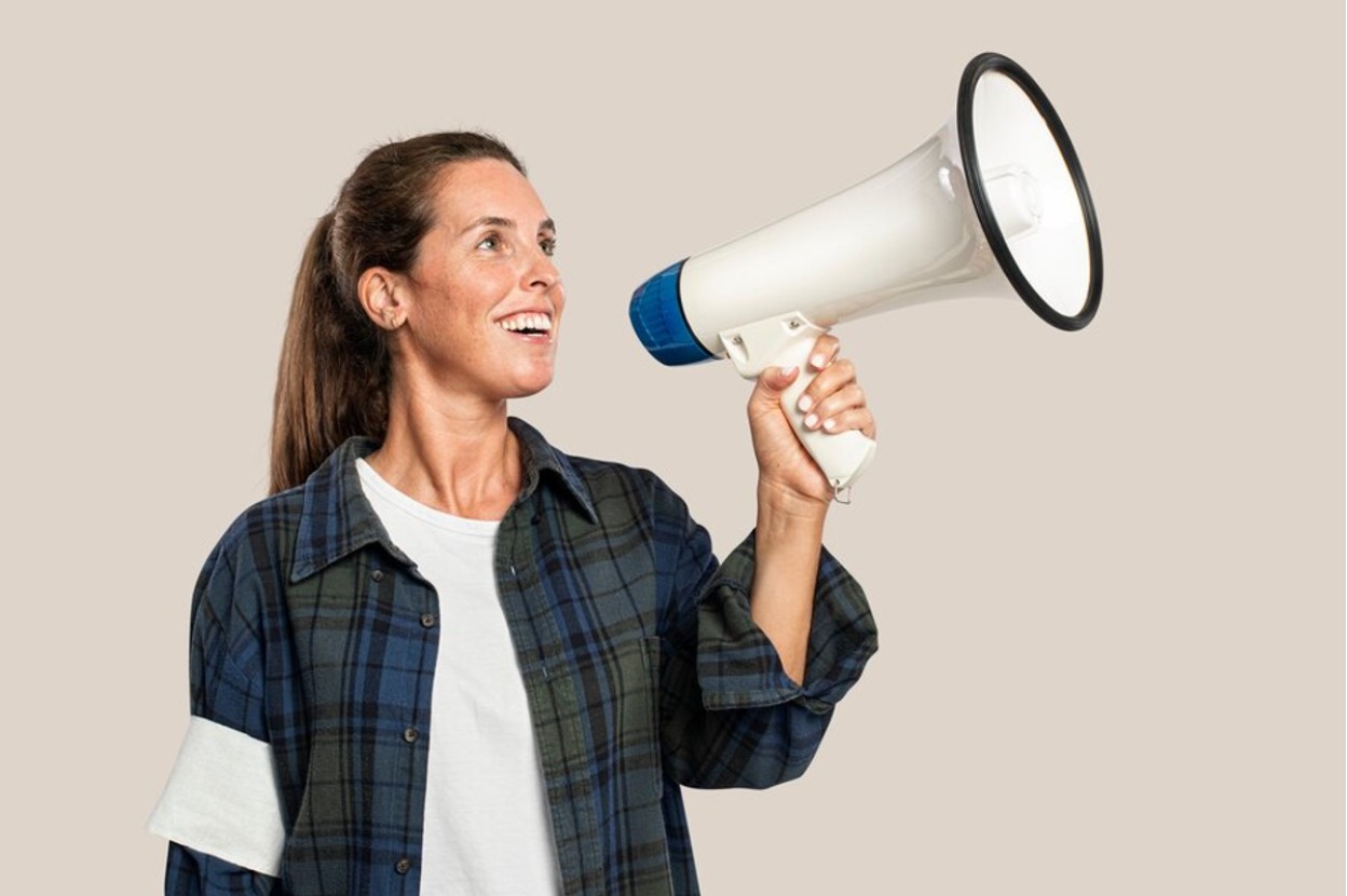 A woman smiles as she speaks into a megaphone