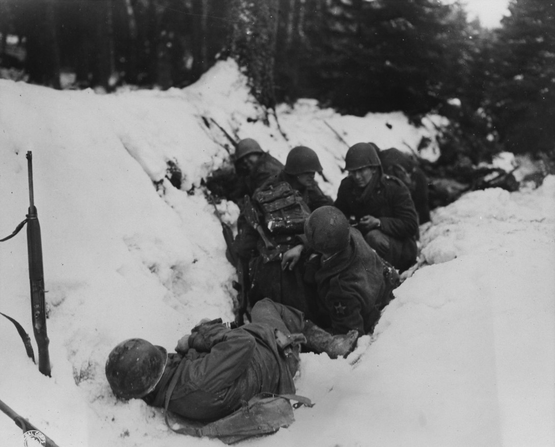 Several soldiers lay in the snow in Germany during WWII