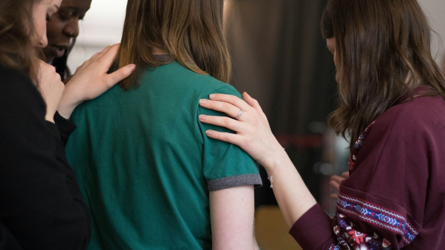 Women standing around another and comforting her.