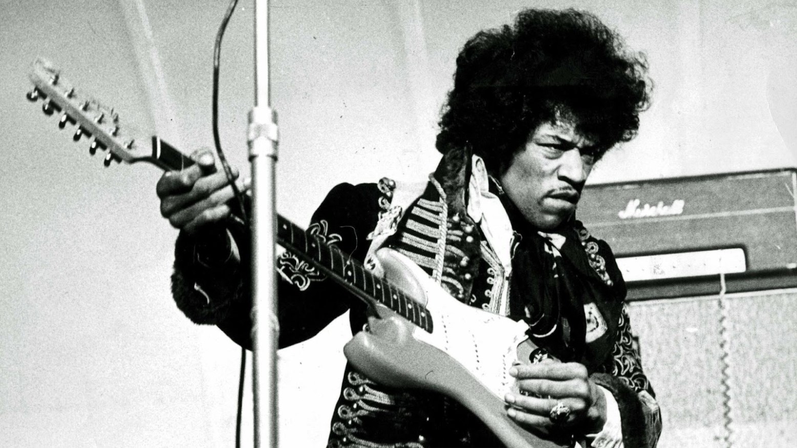 A black and white photo of Jimi Hendrix playing the guitar in 1967.