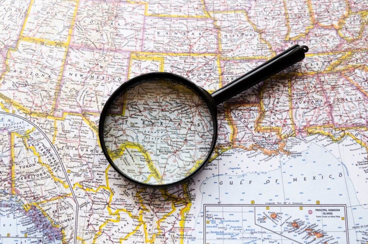 A photograph of a map of the United States with a magnifying glass on top