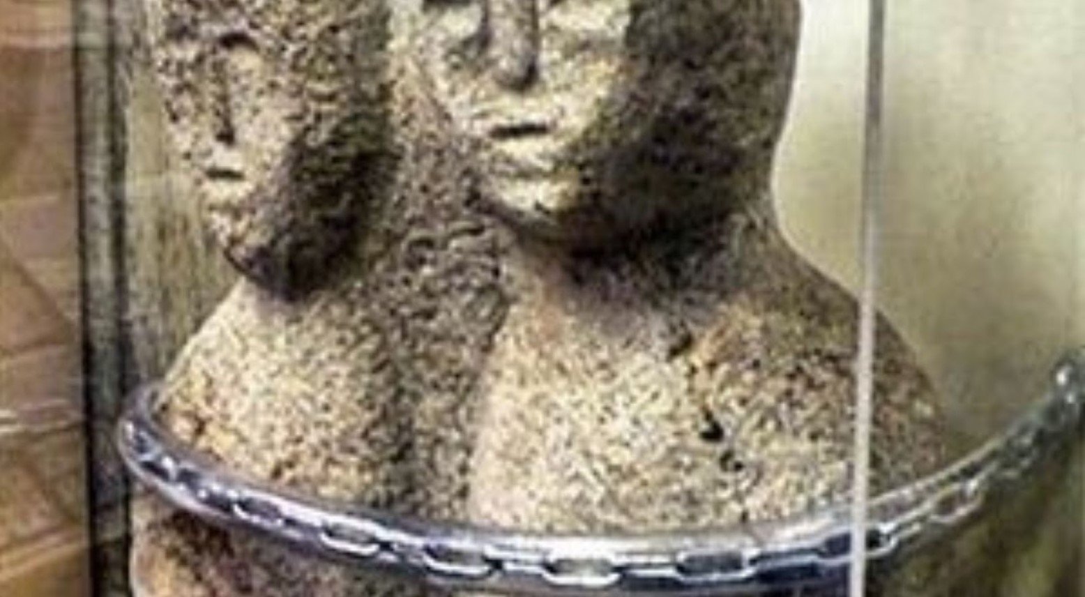 The statue of the moon-eyed people. The statue consists of two people whose heads are attached. A chain is around them that is attaching them to the wall.