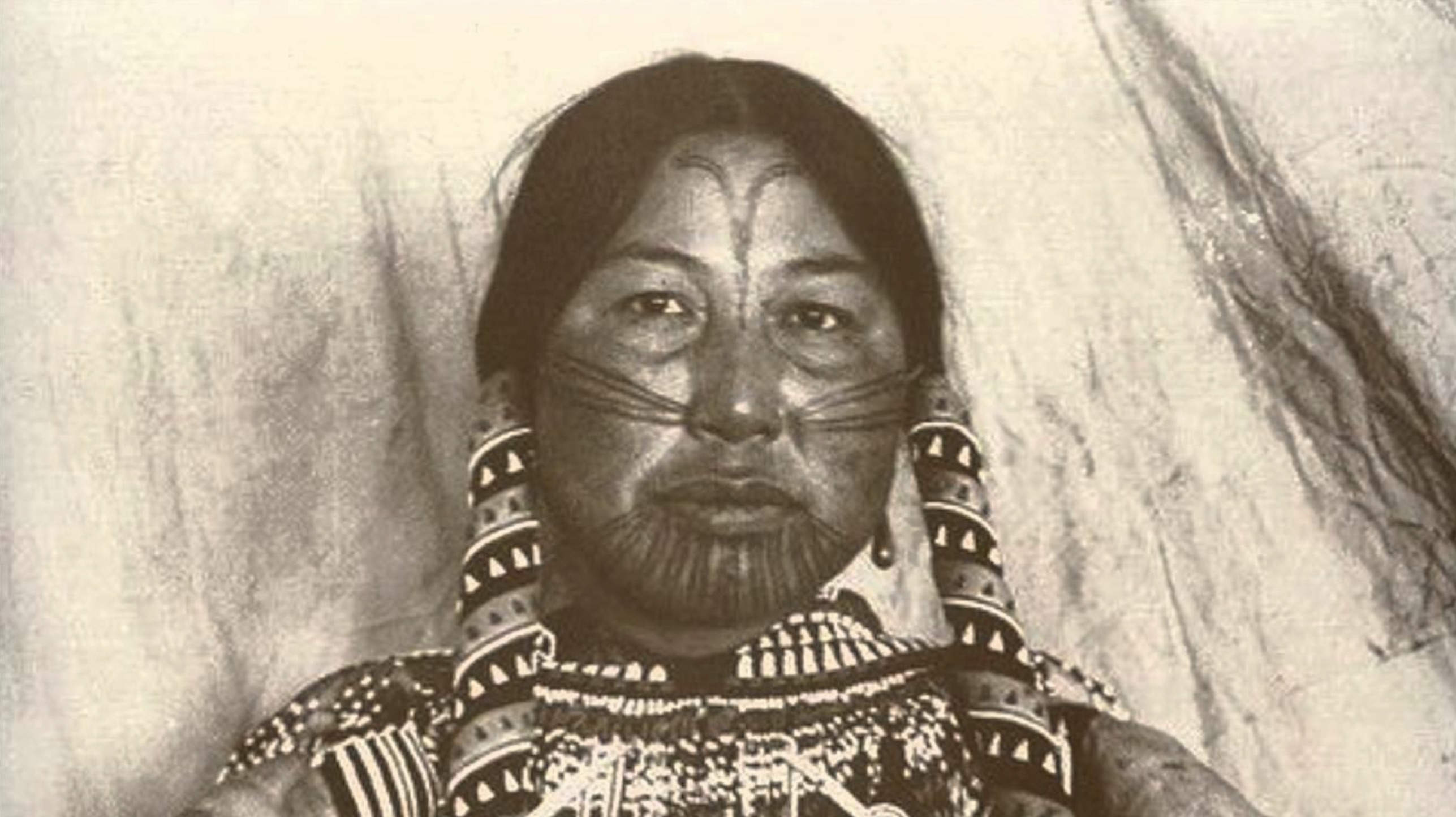 A photograph of a Native American woman with ceremonial tattoos on her face