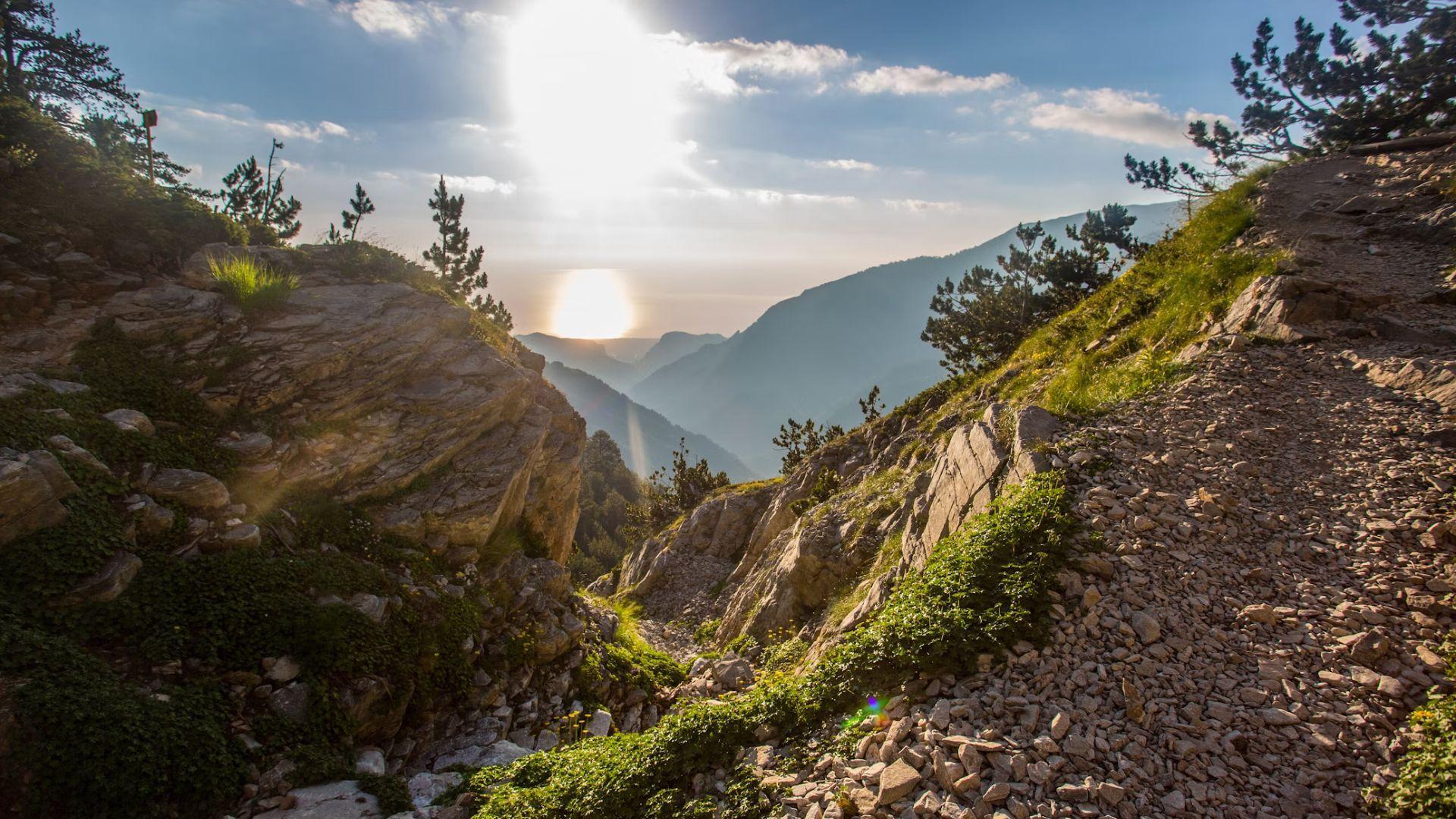 A view of Mount Olympus. The sun is shining in the distance.