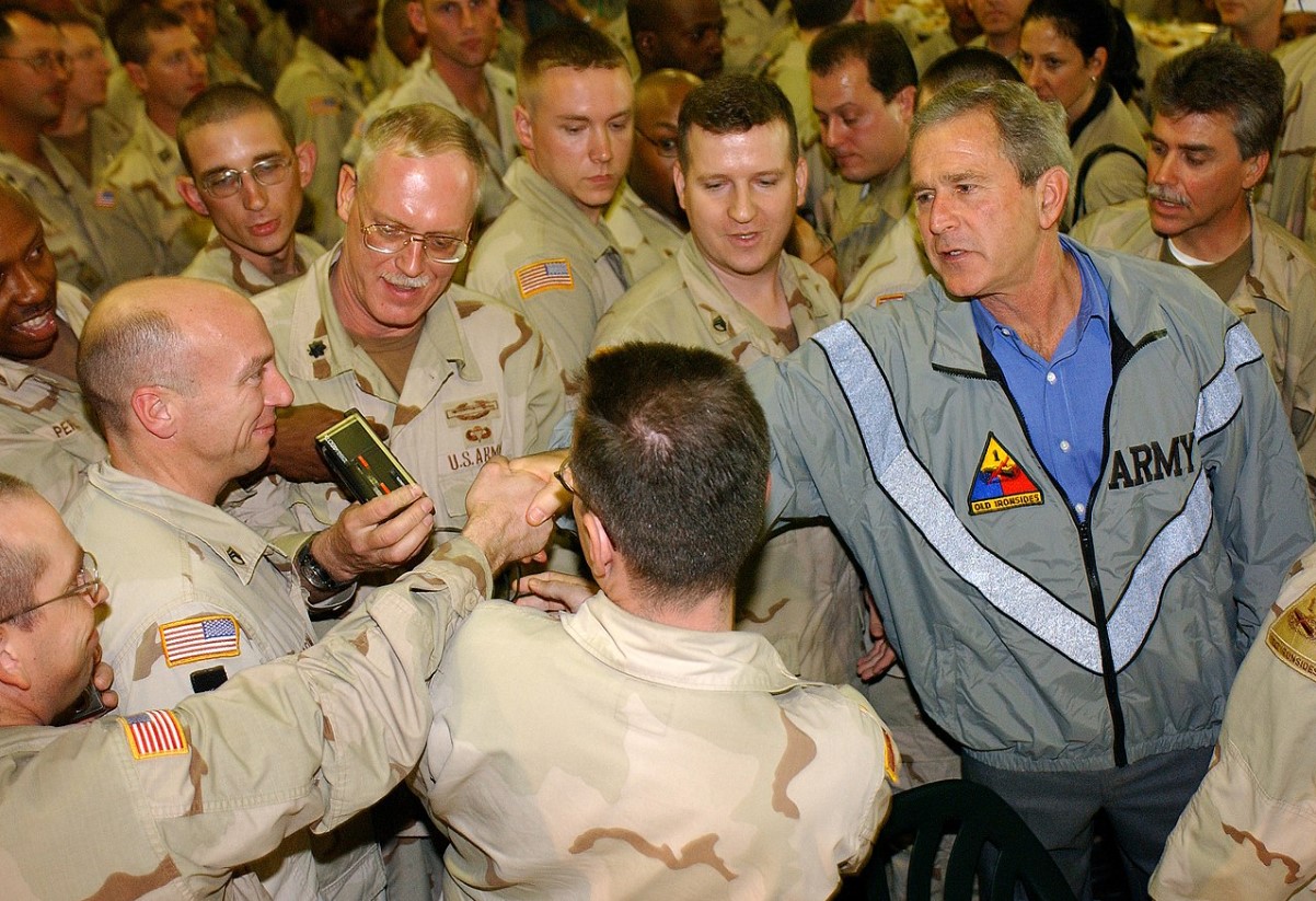 An image of Geroge Bush Jr. speaking with several soldiers