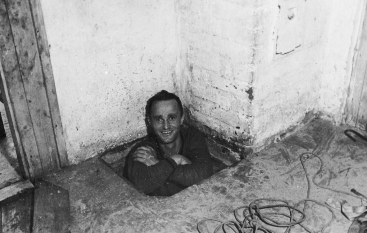 Corporal Karl Greise, one of the German guards known as "Rubberneck,” in the entrance to the escape tunnel "Tom" at Stalag Luft III, 1943