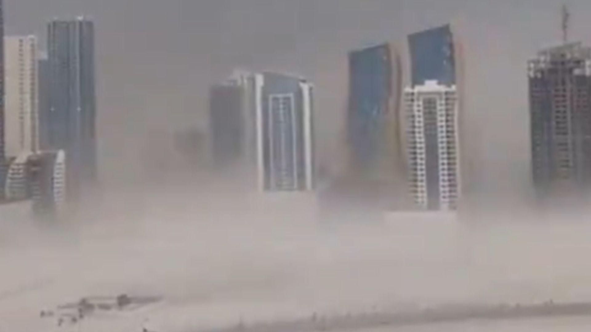 A screenshot from a video showing the storm in Dubai. Most of the sky is grey and there is lots of dust and sand swirling around due to the high winds.