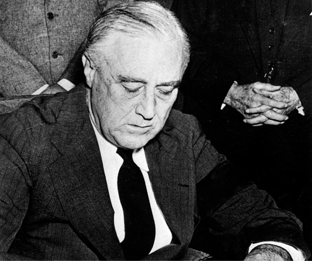 An image of Franklin Roosevelt signing the declaration of war against Japan