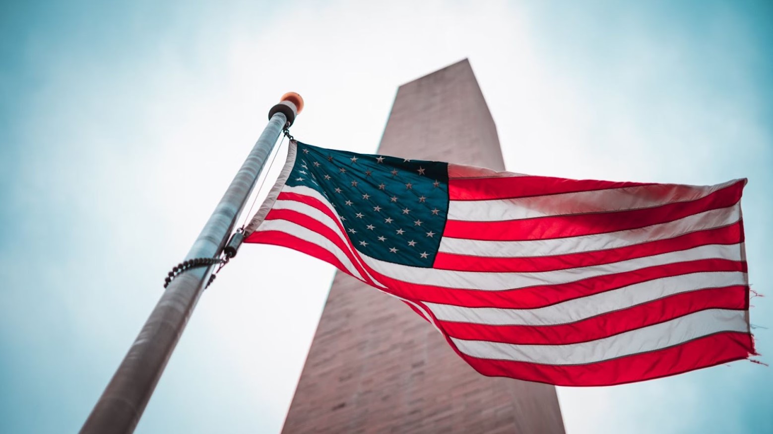 The US flag on a flagpole in front of a building.