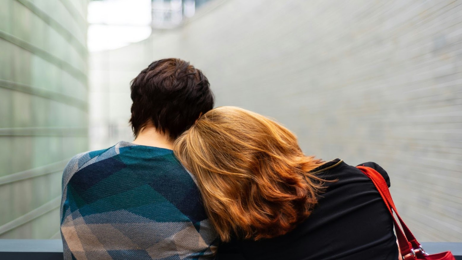 A person leaning their head on another’s shoulder.