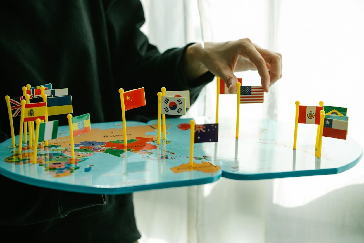 Various nation’s flags pinned on a world map in front of a person
