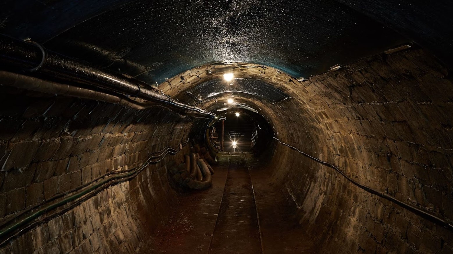 Underground in a sewage tunnel. There is a light at the end of the tunnel.