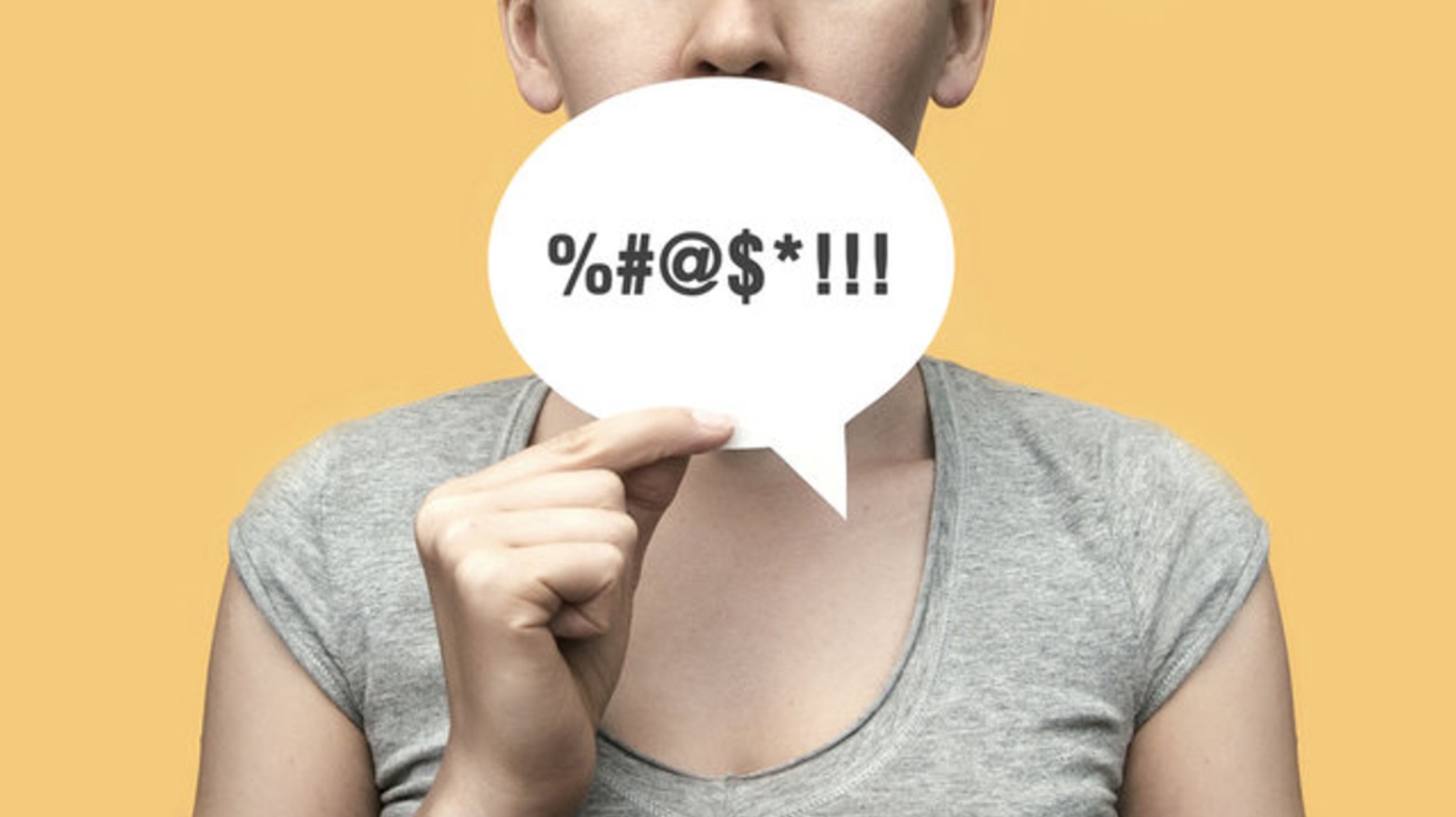 A woman holding a piece of paper with symbols in replace of letters signifying explicit language