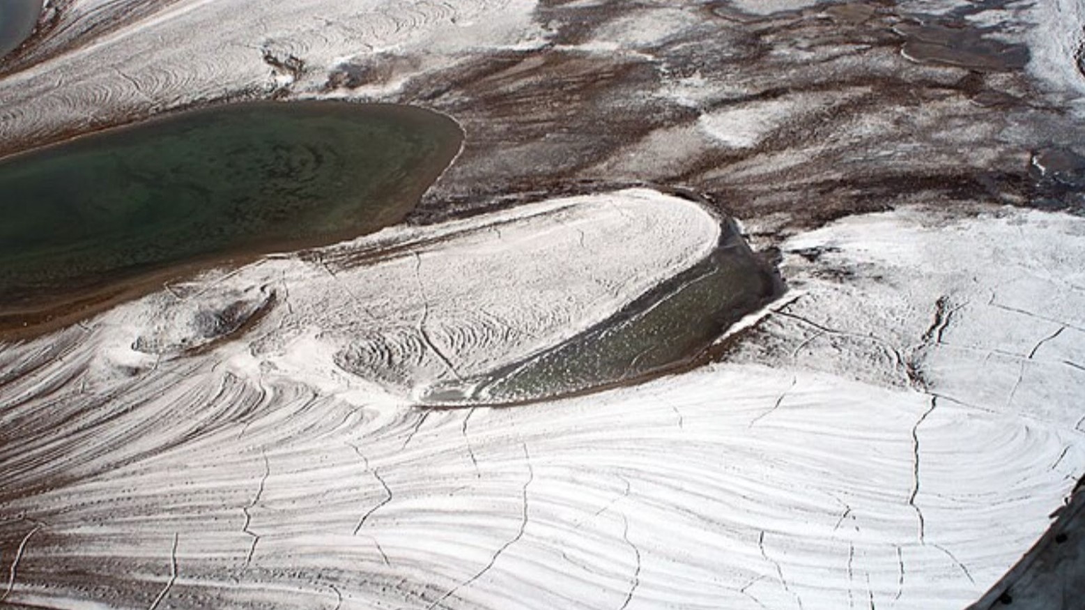 An aerial view of Arctic permafrost. The permafrost is white and has cracks in it.