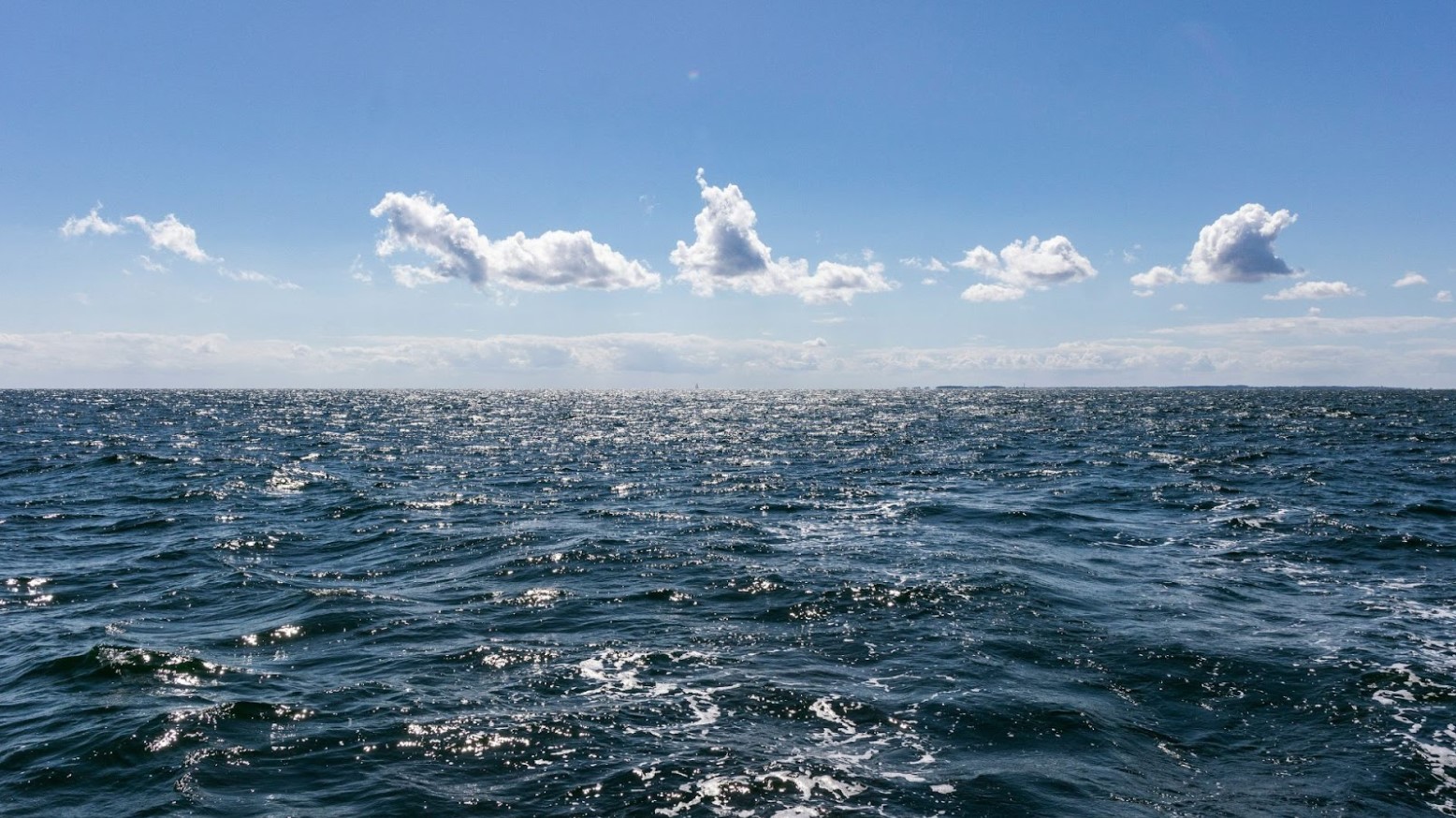 The Baltic Sea seen underneath a cloudy blue sky in the daytime.