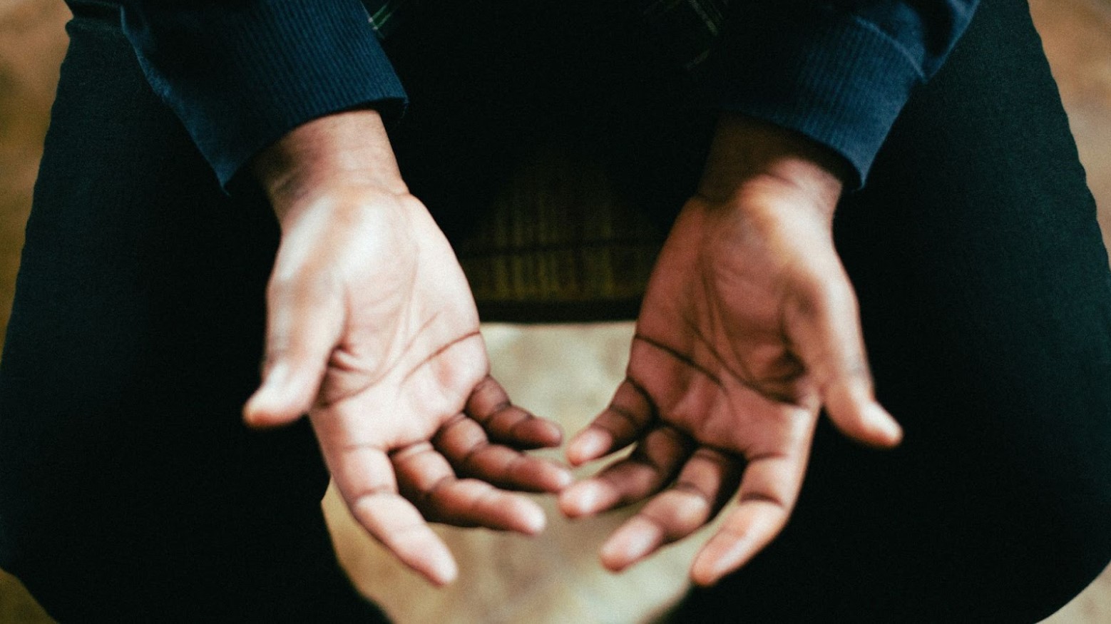 A close-up of a person’s open hands as they sit on a chair.