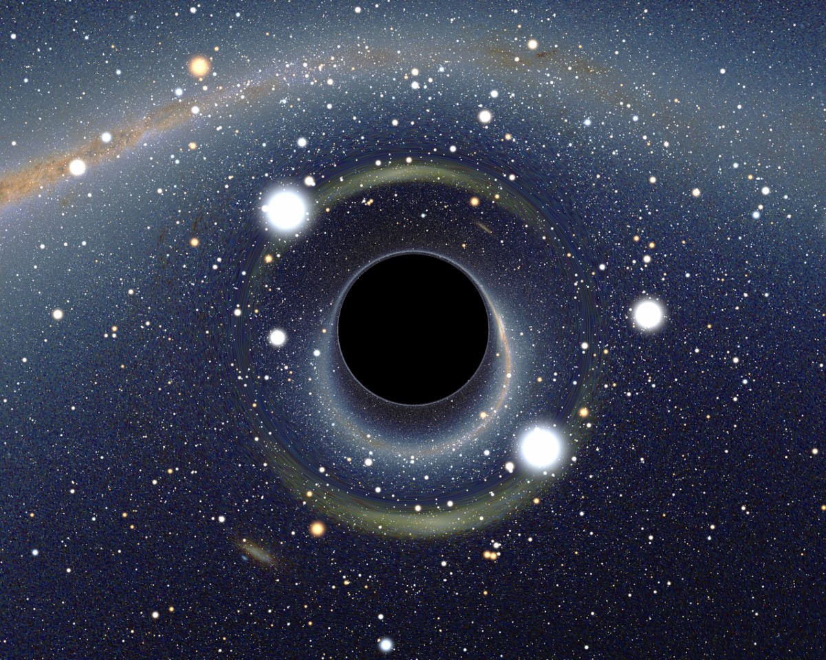 An image of a supermassive black hole with several stars surrounding it