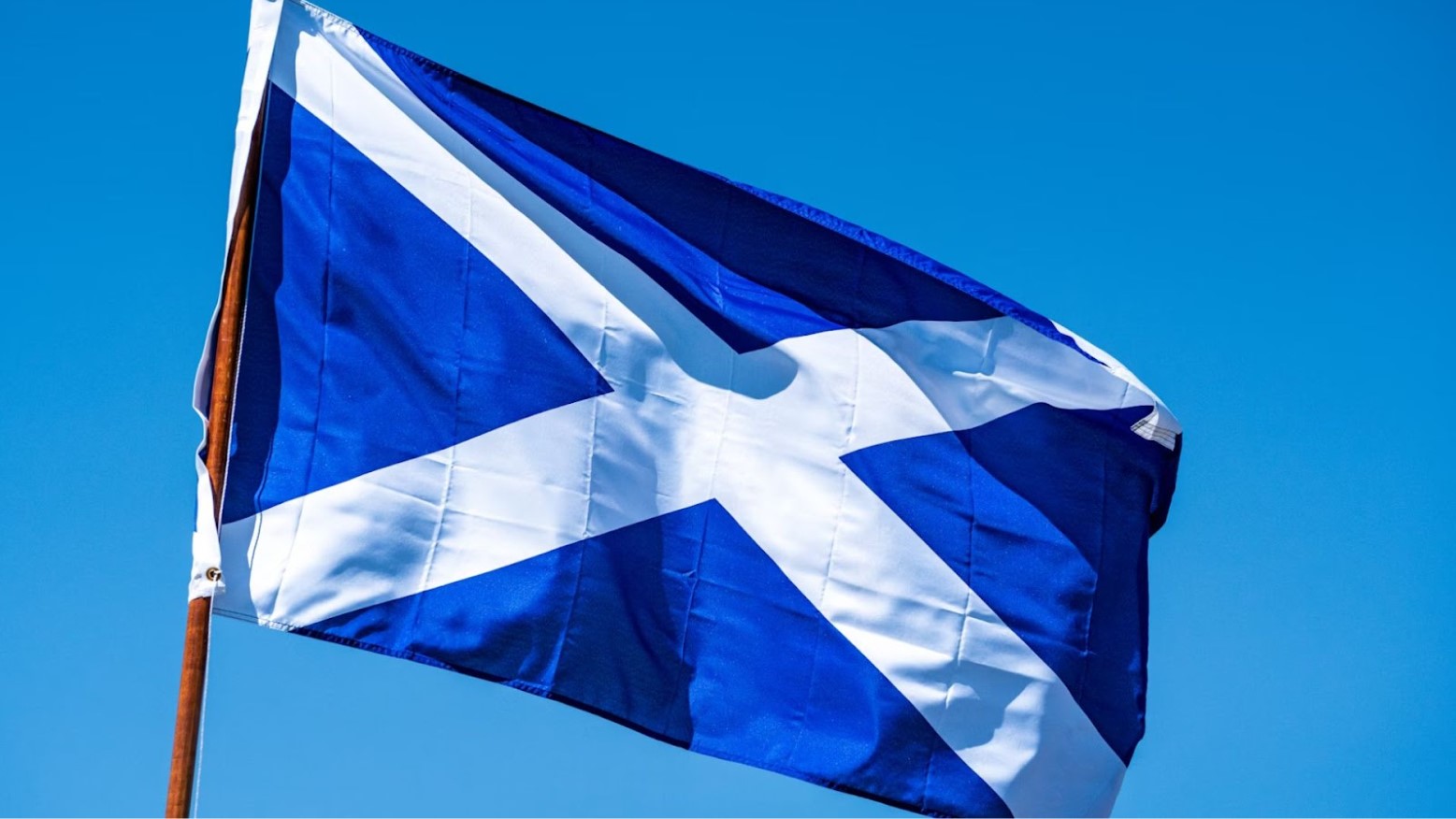 The Scottish flag is a white cross against a blue background on a flagpole.