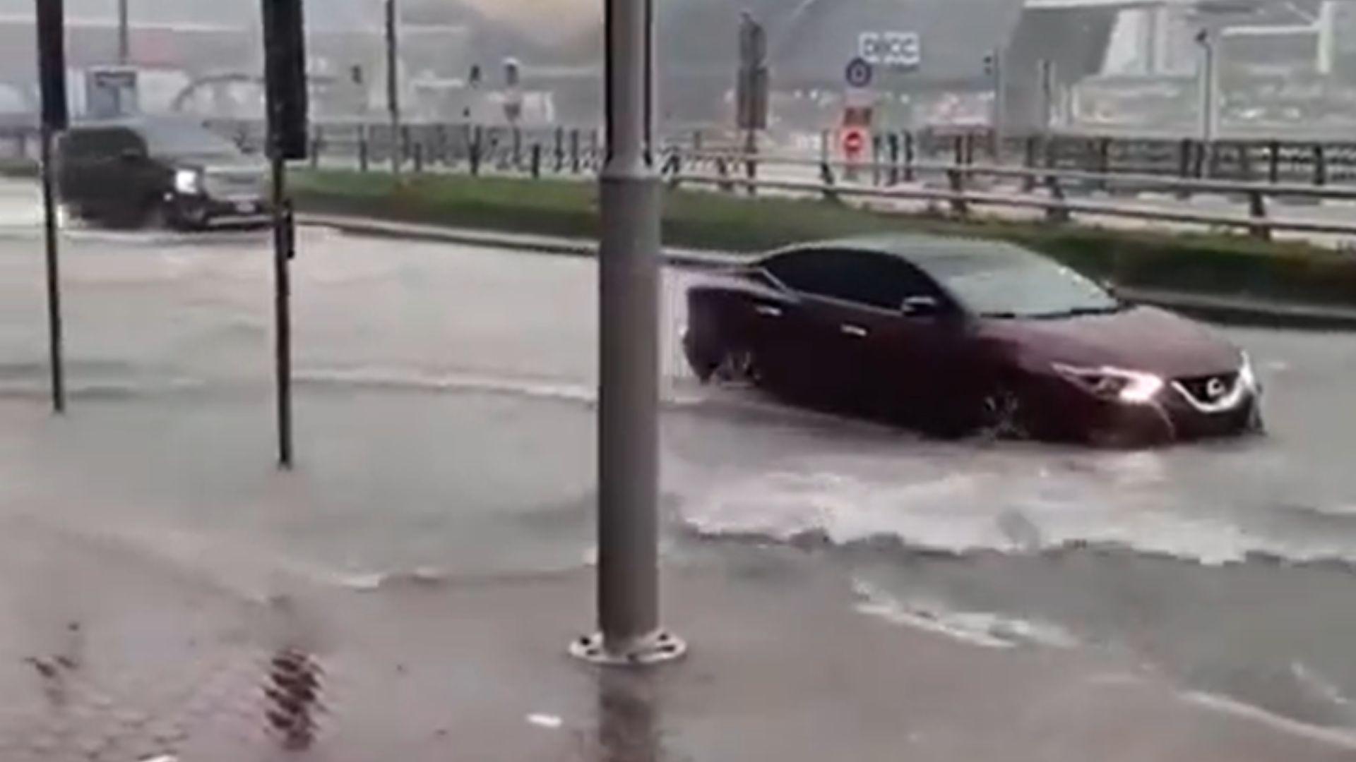 Two cars struggling to drive through the floods in Dubai. The flood water is halfway up each car's tires.