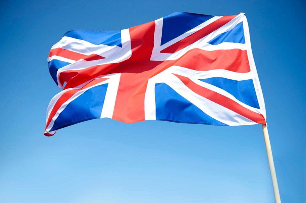 A large British flag flies against a blue sky