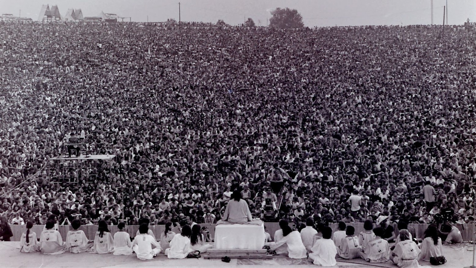 A view of performers on a stage and a huge crowd in front of them at Woodstock.