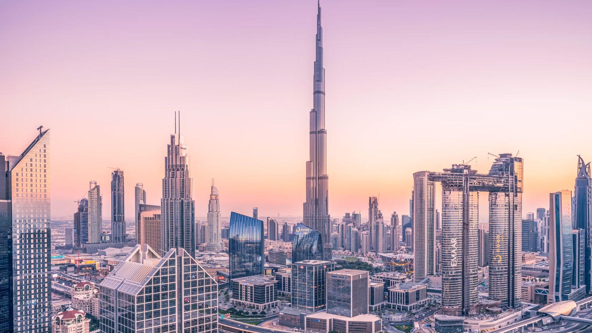 Dubai during the day when it’s not flooded. There are high-rise buildings and clear roads.