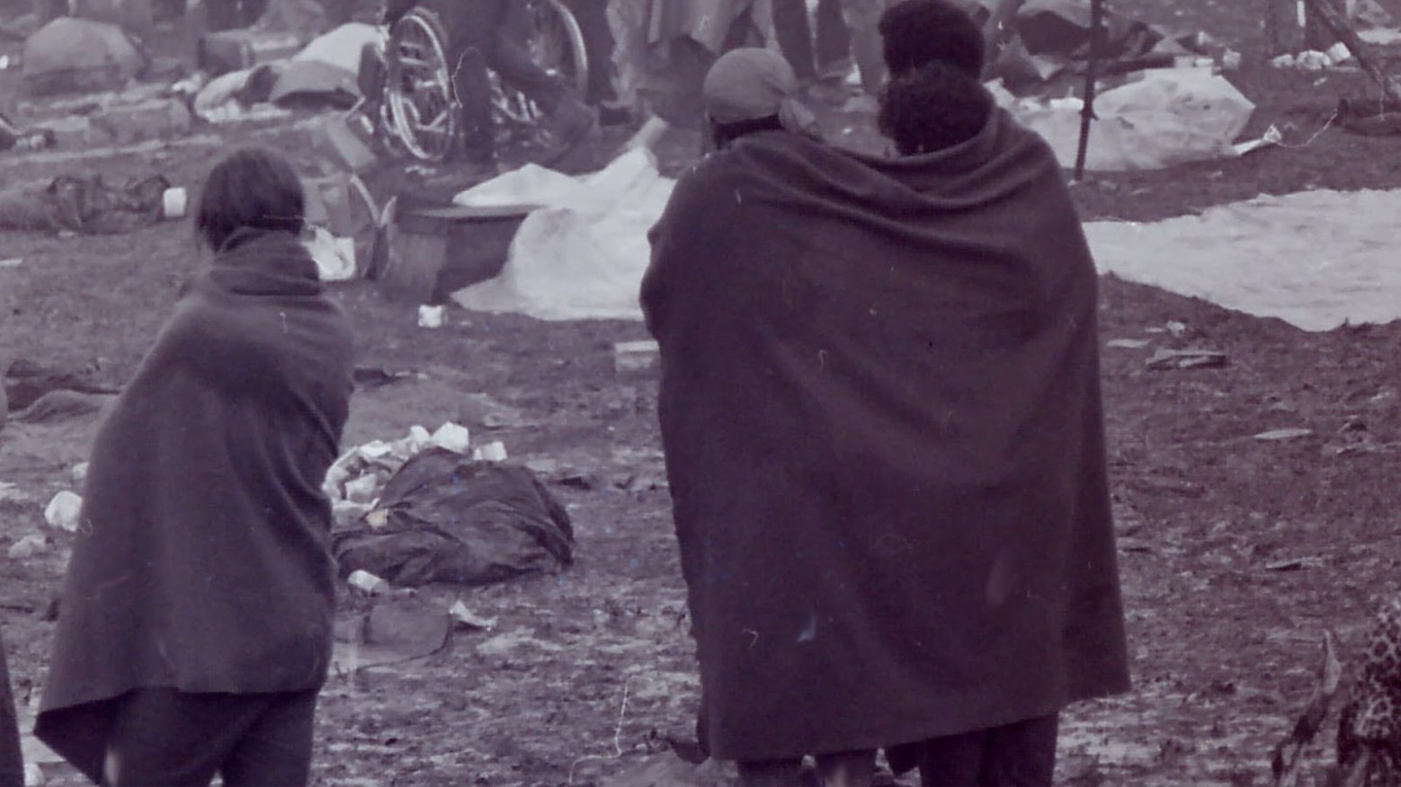 Three people in the mud in towels at Woodstock in 1969.