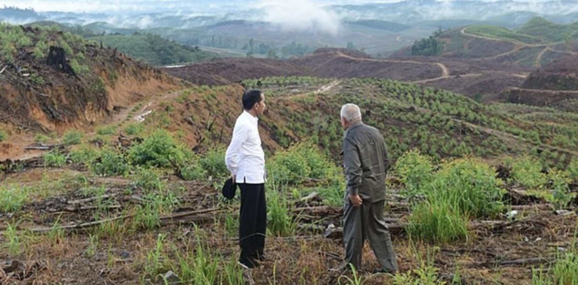 The site where Nusantara will be built. Two men are standing on the site. They are looking into the background, which has hills and clouds.