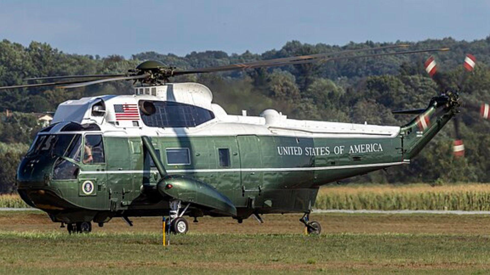 The VH-3D helicopter. The helicopter is green and white and has the American flag logo. The words “United States of America” at the end of the helicopter.
