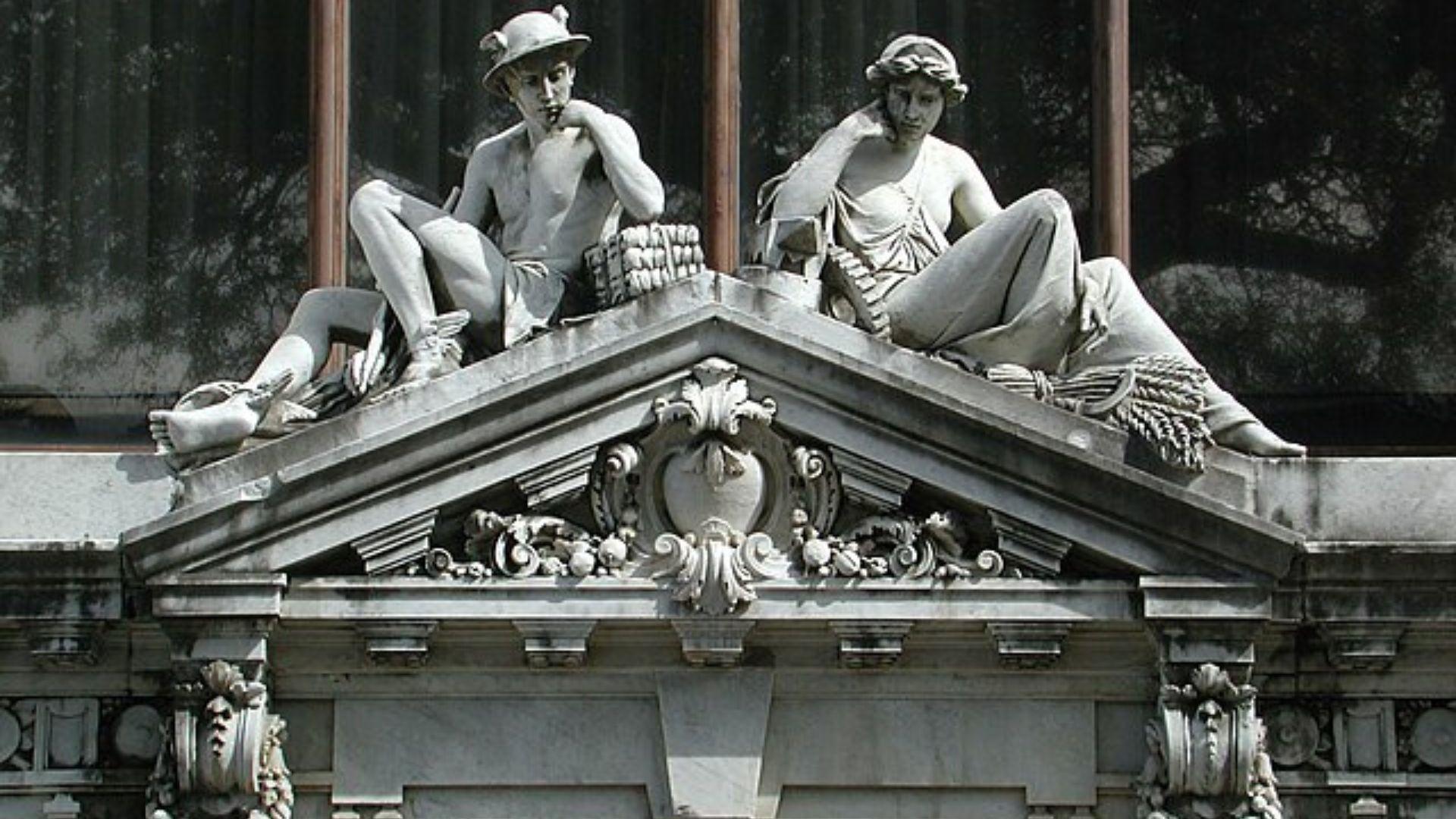 Two statues of Greek Gods on top of a roof.