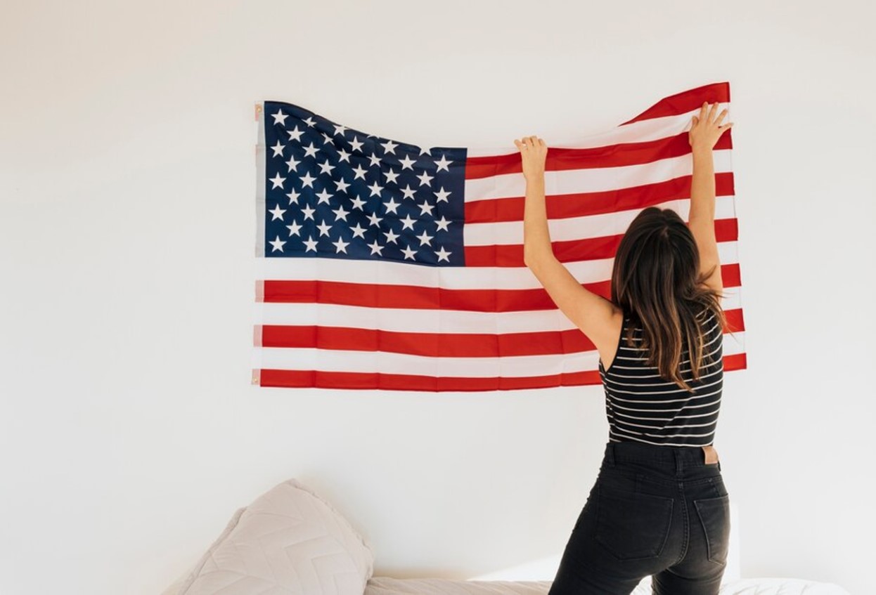 A woman puts an American flag up in her living room above the couch