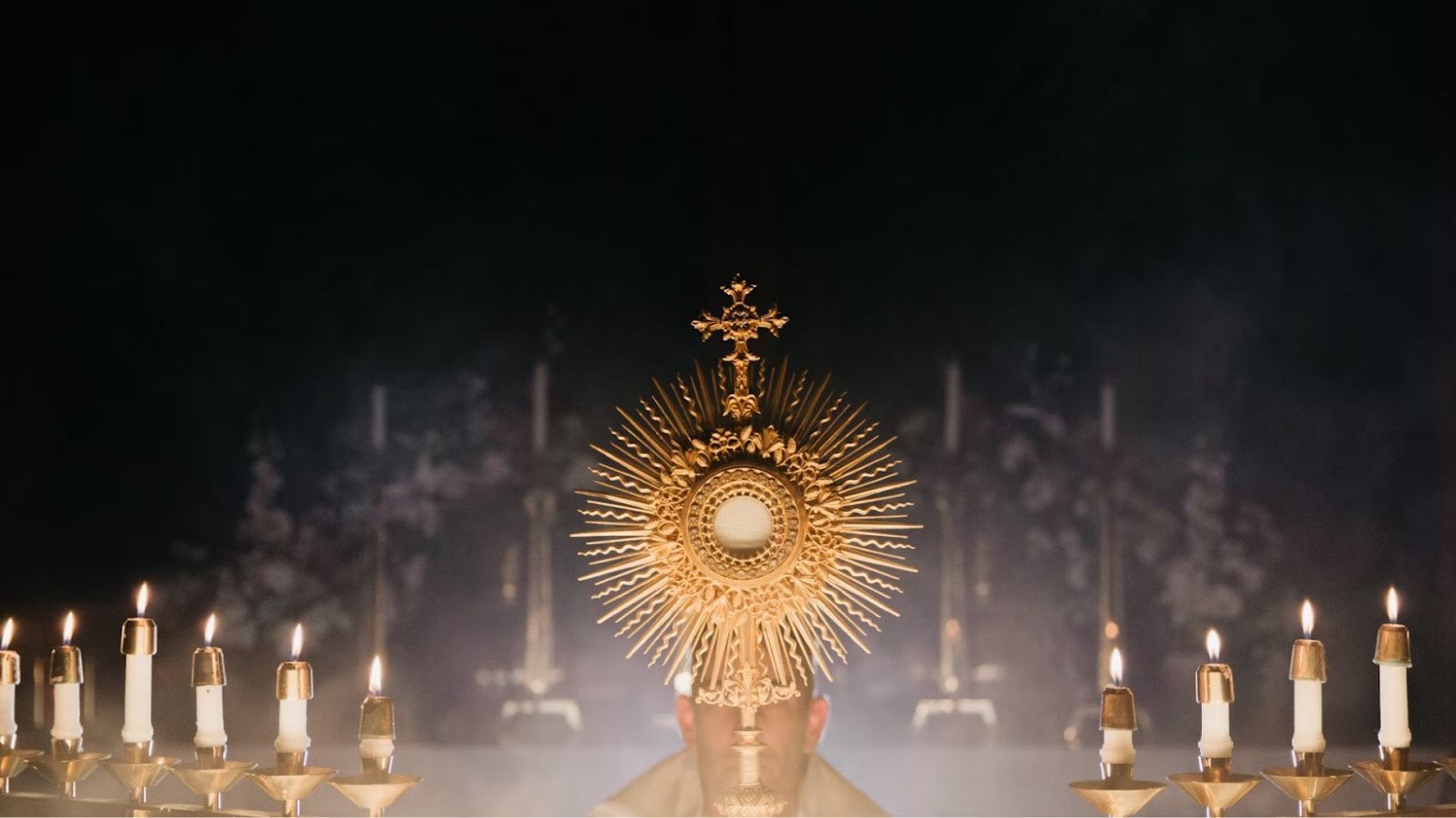 A Monstrance, which is used in the Roman Catholic Church. The Priest is carrying the Monstrance, which lit candles on either side of him.