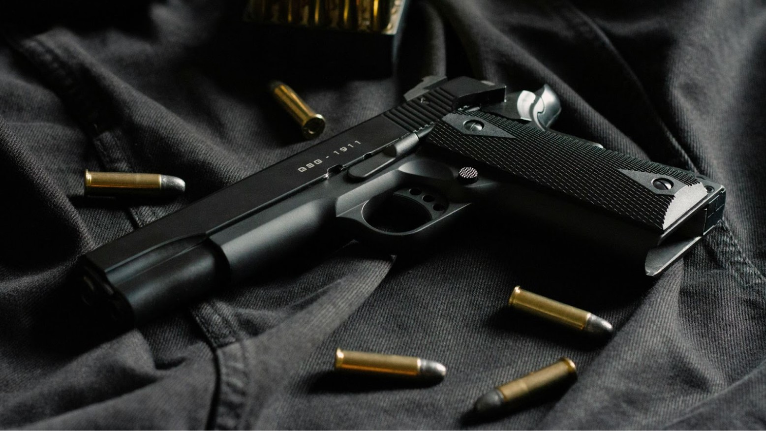 A close-up of a black gun with bullets beside it.