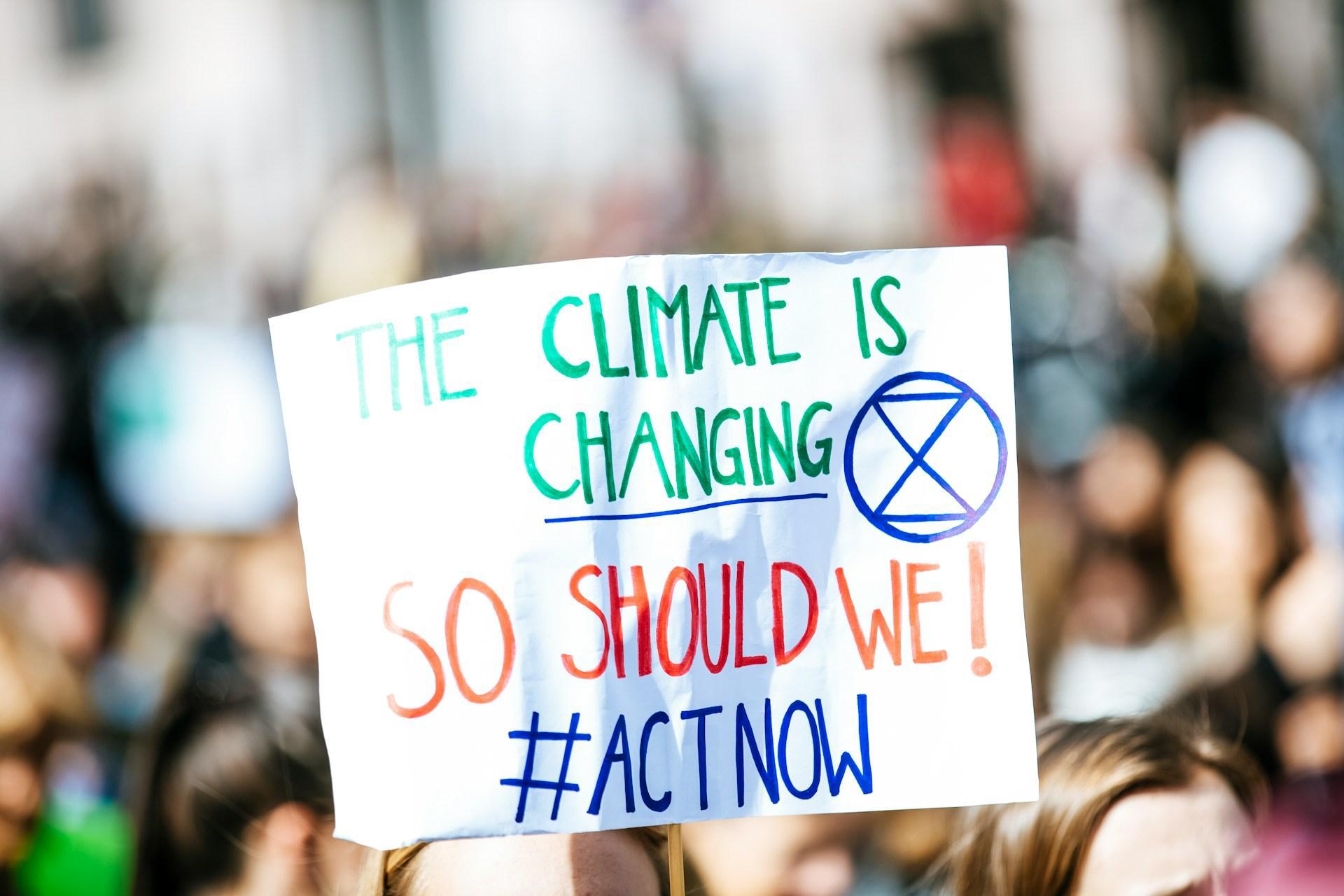 A white sign saying Climate Is Changing at a rally