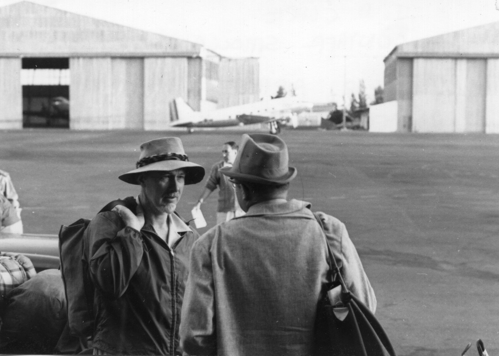 A grayscale image of J. Desmond Clark talking to someone in an airport