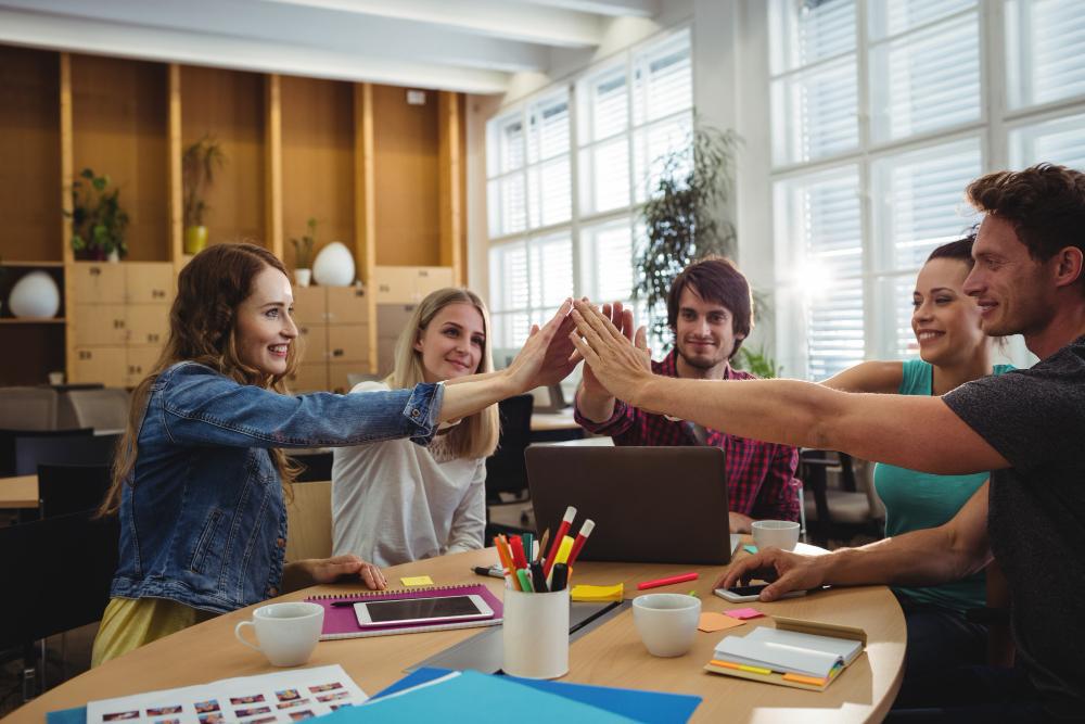 A group is pictured during a high-five as they collectively work at a small company