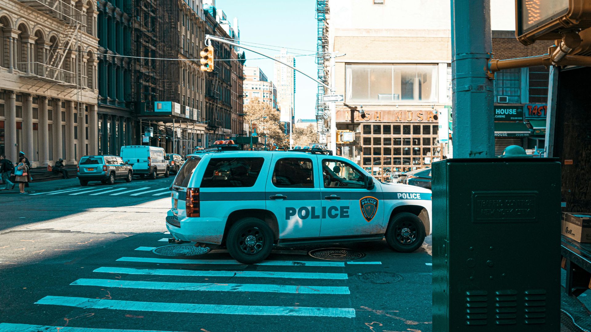 A white police car driving down a road in the daytime.