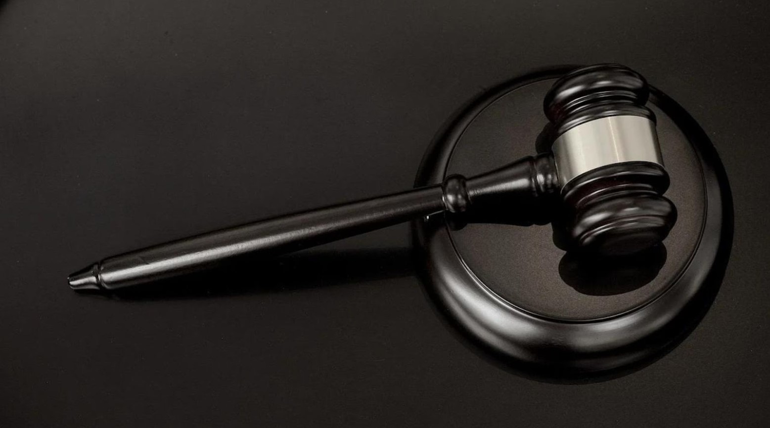 A black gavel lying on a black surface.