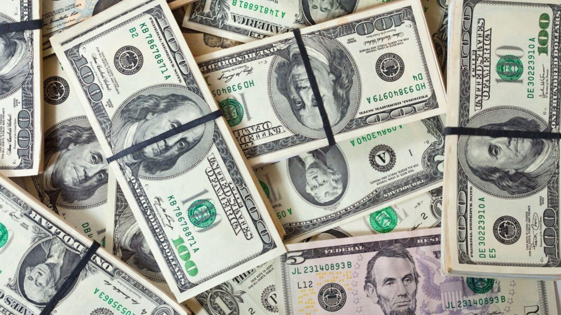A pile of $100 notes attached with a black elastic band.