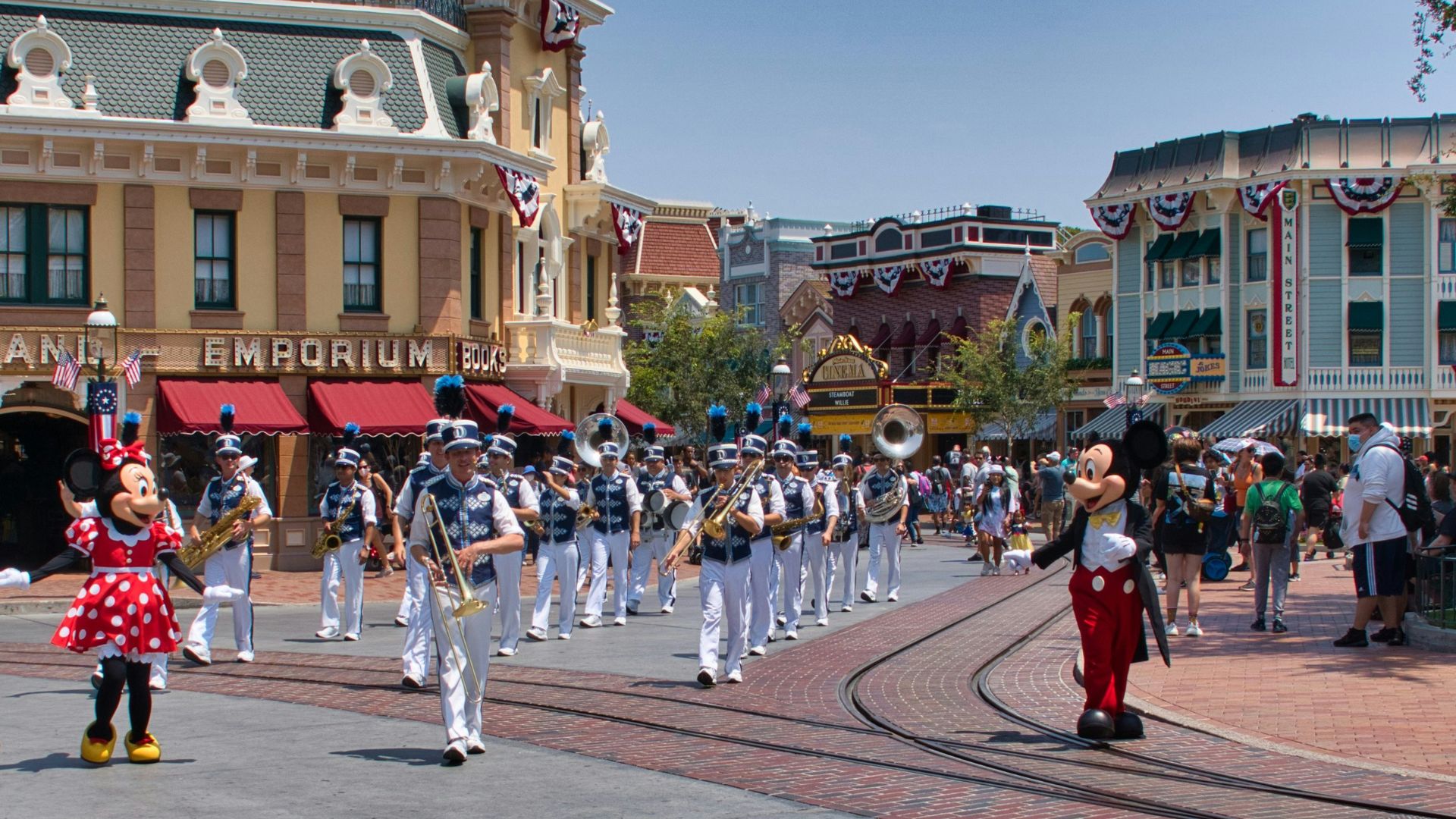 Minnie and Mickey Mouse walking around Disneyland with a band by visitors.