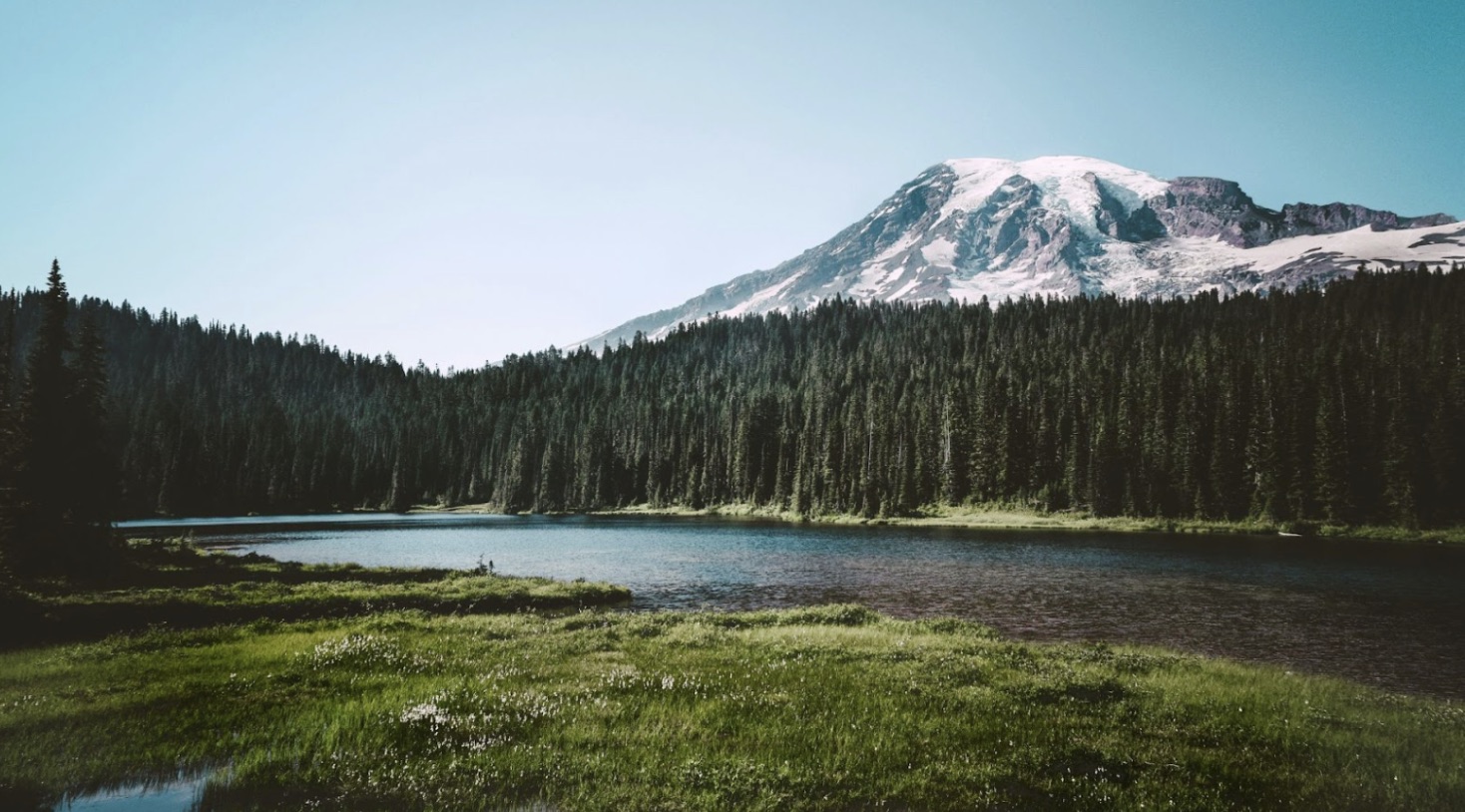 Water and green trees in front of a mountain seen at a Washington state park.