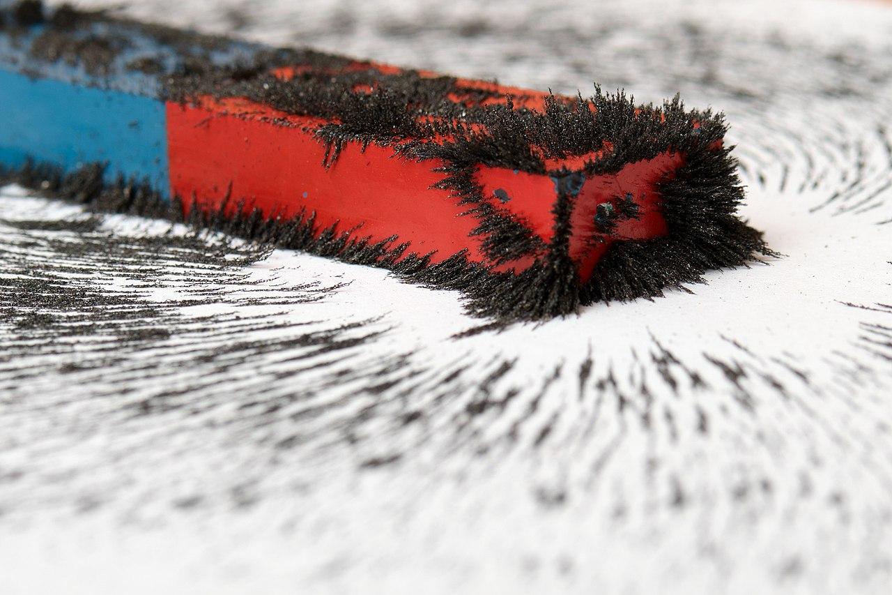 A photograph which shows several shards of metal sticking to a magnet