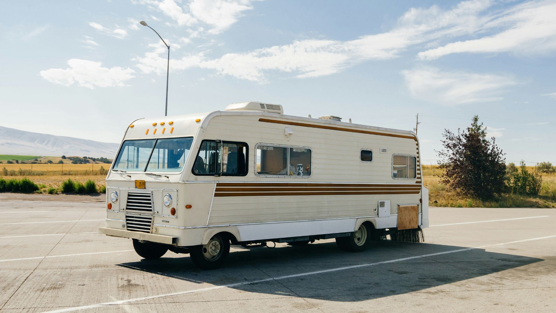 An old RV parked in a parking lot in the daytime.
