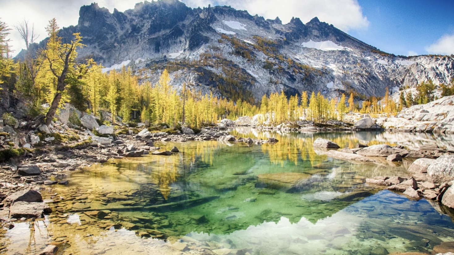 Water, rocks, and bushes seen in front of a mountain at Enchantment Peaks, Washington.