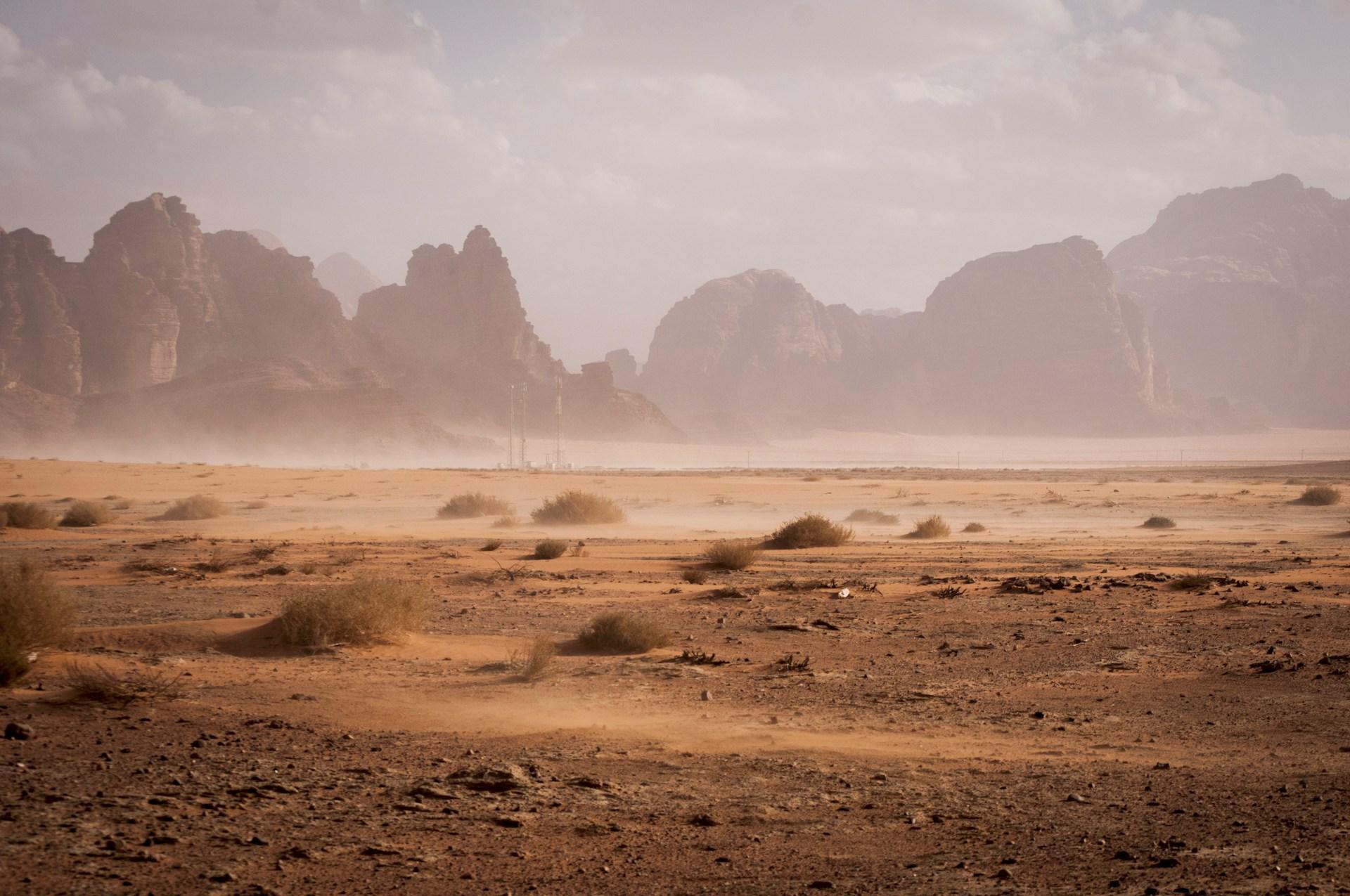A dusty desert valley with rocky mountains in the distance
